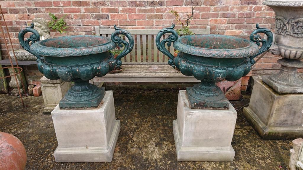 <p>Pair of French style cast iron urns on reconsituted stone plinths.</p>